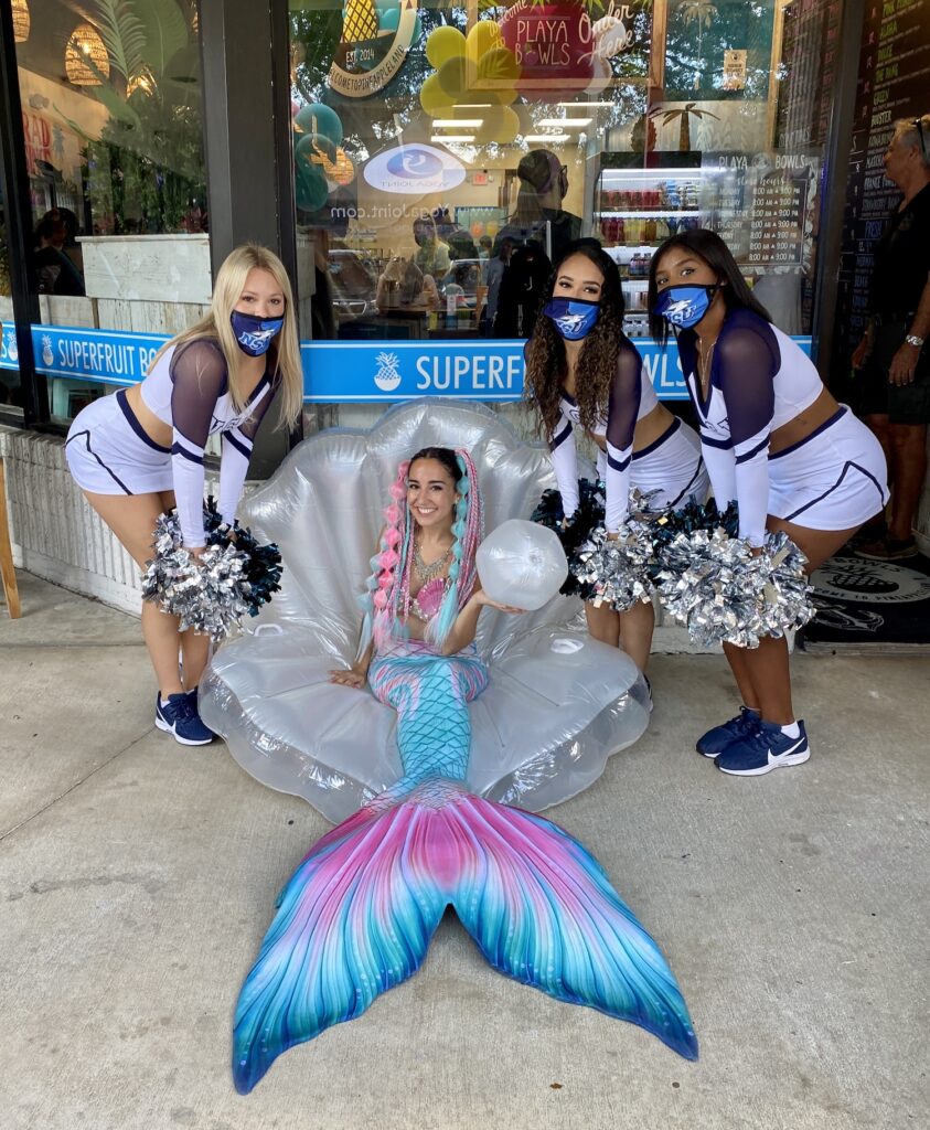 Cheerleaders gather around Mermaid Jules in her clamshell throne as they celebrate Playa Bowls Davie Grand Opening!