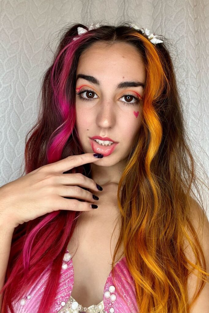 Pink and Orange hair color with a mermaid wave, done up in pigtails
