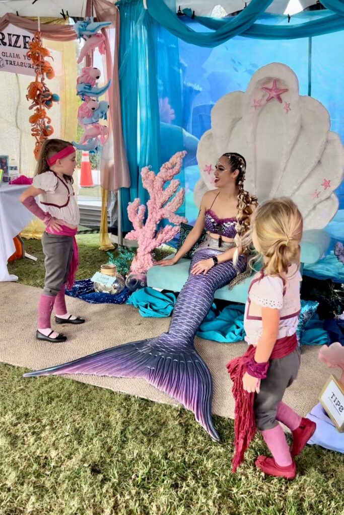 Two girls in pirate costumes meet a mermaid in her clam throne